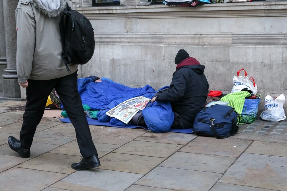 homeless person on the streets with a sleeping bag and newspaper